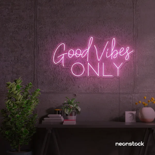 Baby pink neon sign that says Good Vibes Only against a dark wall.