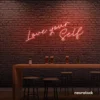 Love Yourself neon sign in peachy pink for self-love decor, beauty rooms, and empowering spaces.