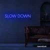 Slow Down neon sign in dark blue for relaxation spaces, wellness decor, and mindful interiors.