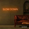 Slow Down neon sign in orange for relaxation spaces, wellness decor, and mindful interiors.