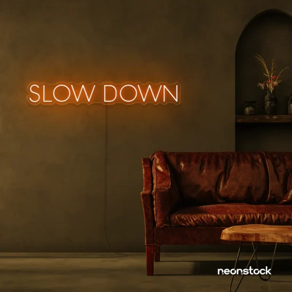 Slow Down neon sign in orange for relaxation spaces, wellness decor, and mindful interiors.