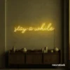 Stay Awhile neon sign in golden yellow for cozy cafes, home decor, and hospitality settings.