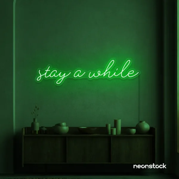 Stay Awhile neon sign in deep green for cozy cafes, home decor, and hospitality settings.
