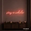 Stay Awhile neon sign in peachy pink for cozy cafes, home decor, and hospitality settings.