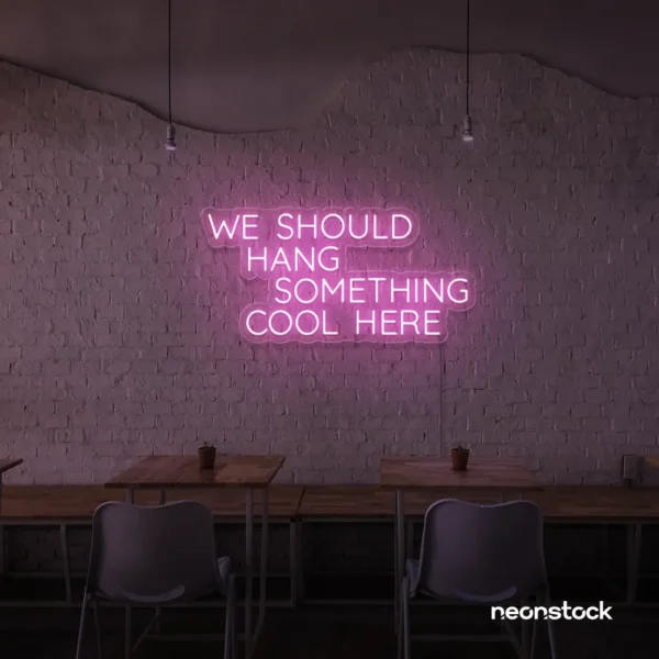 Neon sign text 'We should hang something cool here' in baby pink for wall art and home decor