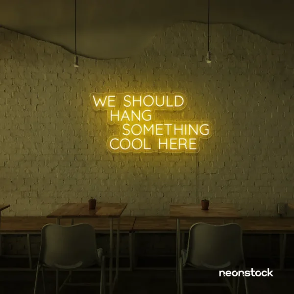 Neon sign text 'We should hang something cool here' in golden yellow for wall art and home decor