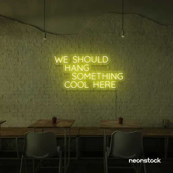 Neon sign text 'We should hang something cool here' in lemon yellow for wall art and home decor