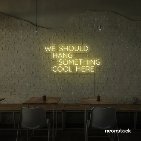 Neon sign text 'We should hang something cool here' in warm white for wall art and home decor